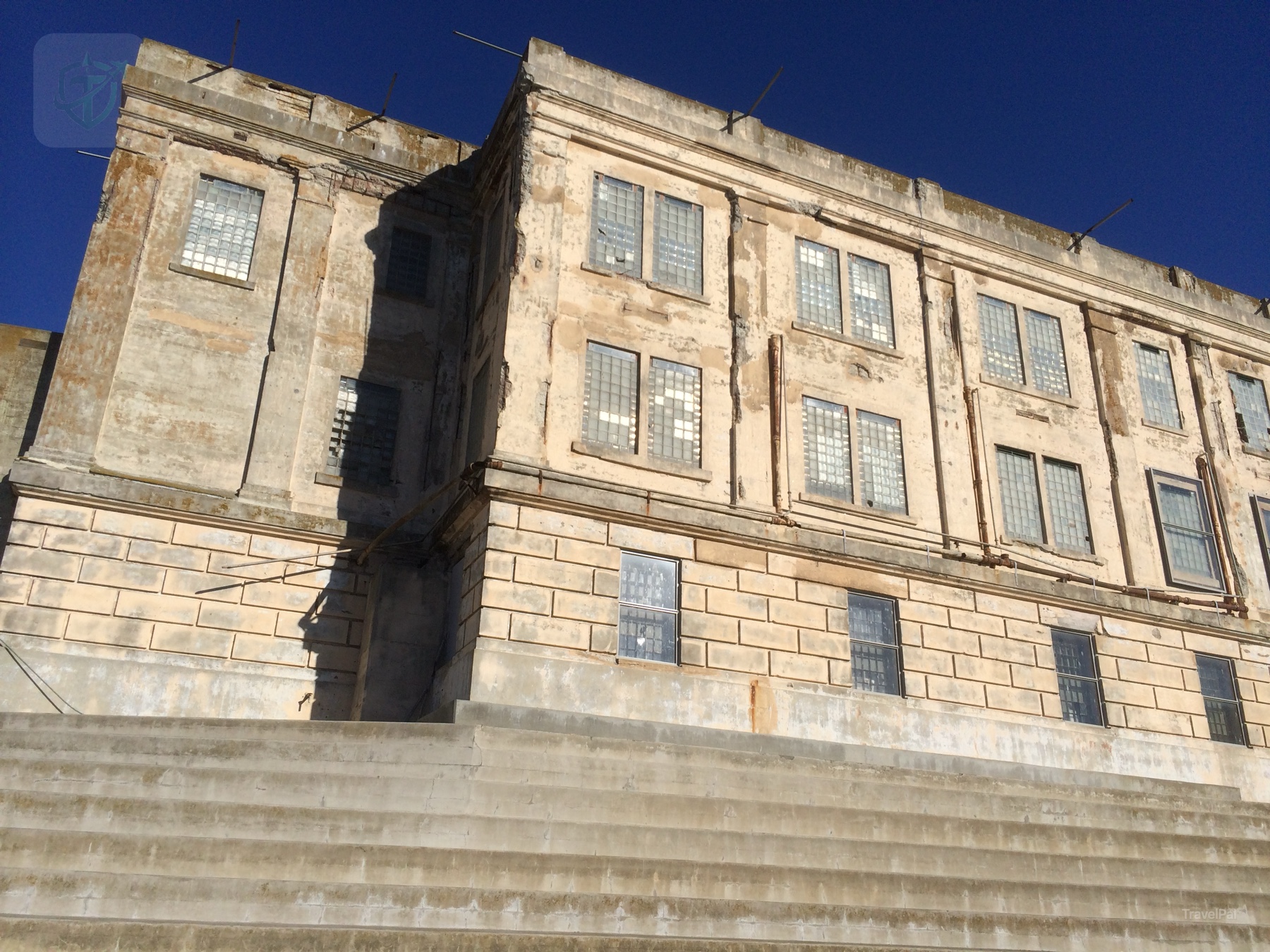 Weathered stone facade of the former Alcatraz cellhouse under a clear blue sky