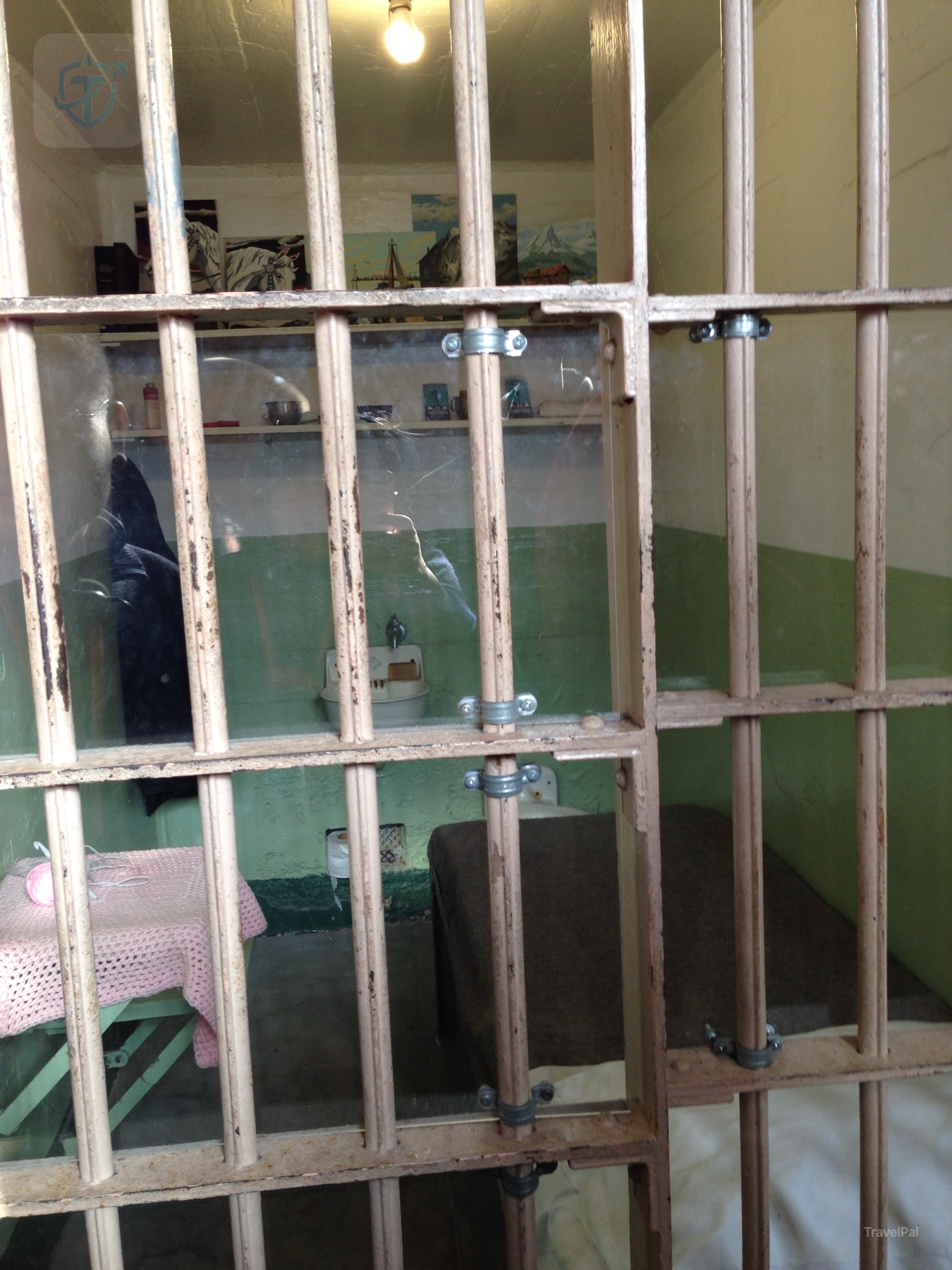 A narrow Alcatraz cell seen through a grid of metal bars