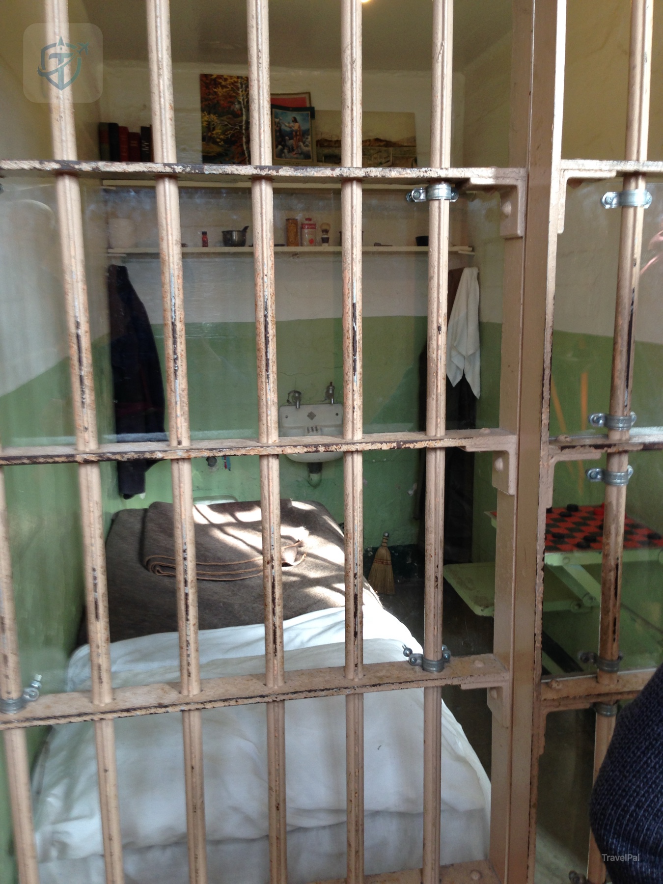 Alcatraz cell with a bed and sink behind weathered metal bars