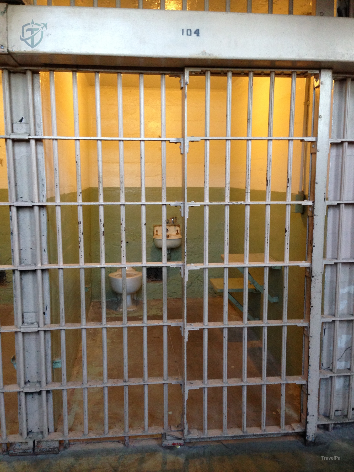 Alcatraz cell door marked 104 with its bed and sink behind bars