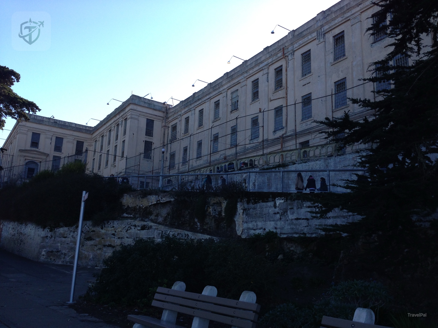 Weathered Alcatraz cellhouse buildings rising above a path and trees