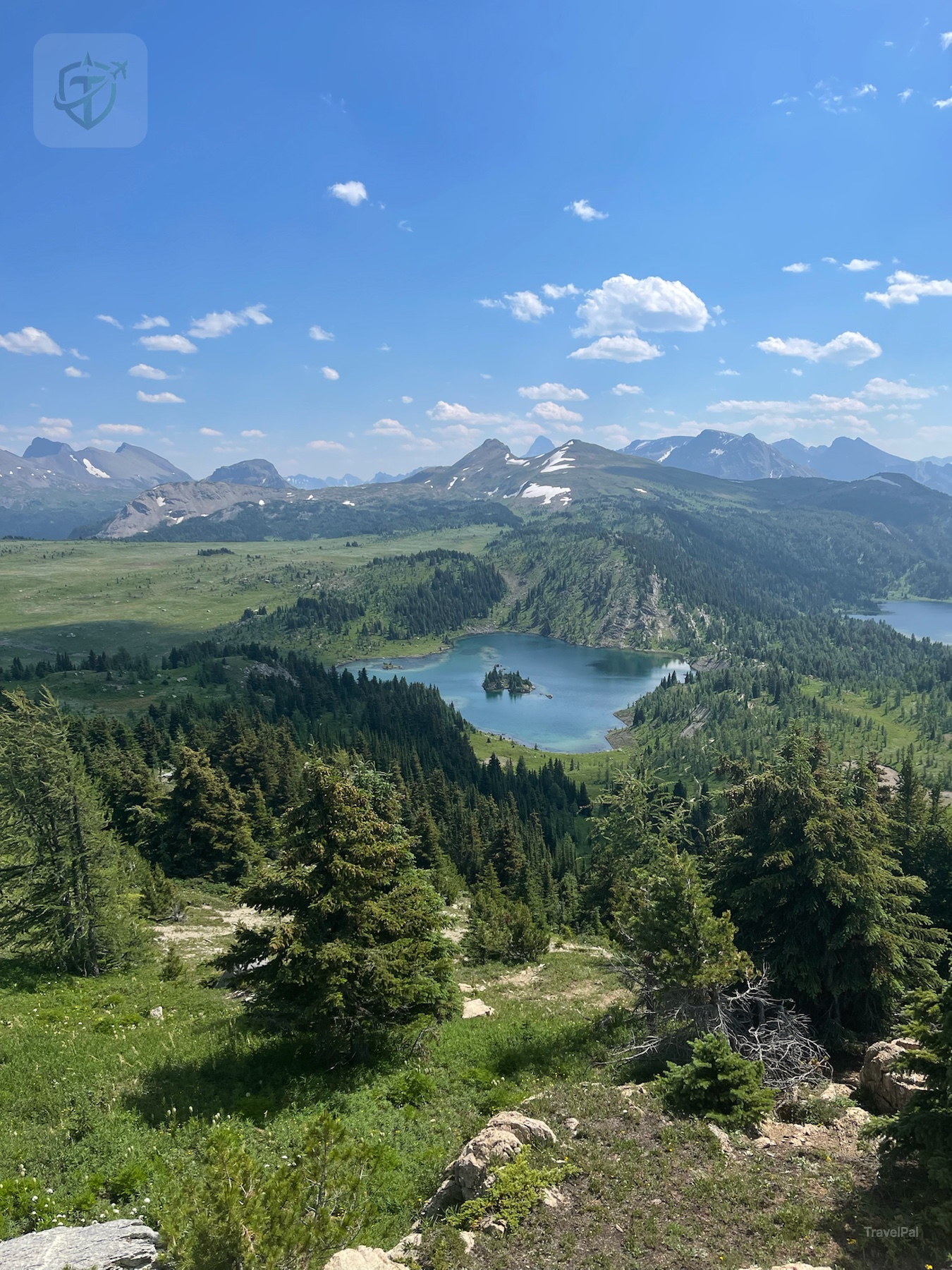 Rock Isle Lake and layered Canadian Rockies beyond a green alpine slope