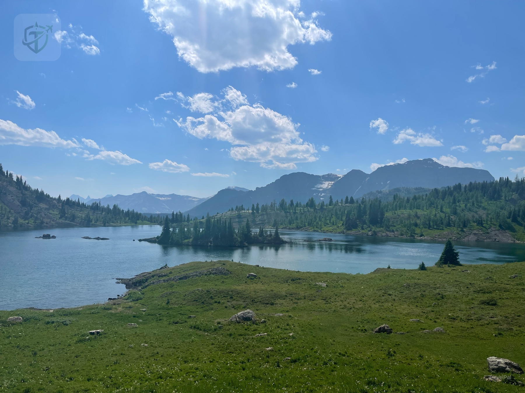 Sunshine Meadows lake and mountain ridge beneath bright summer clouds
