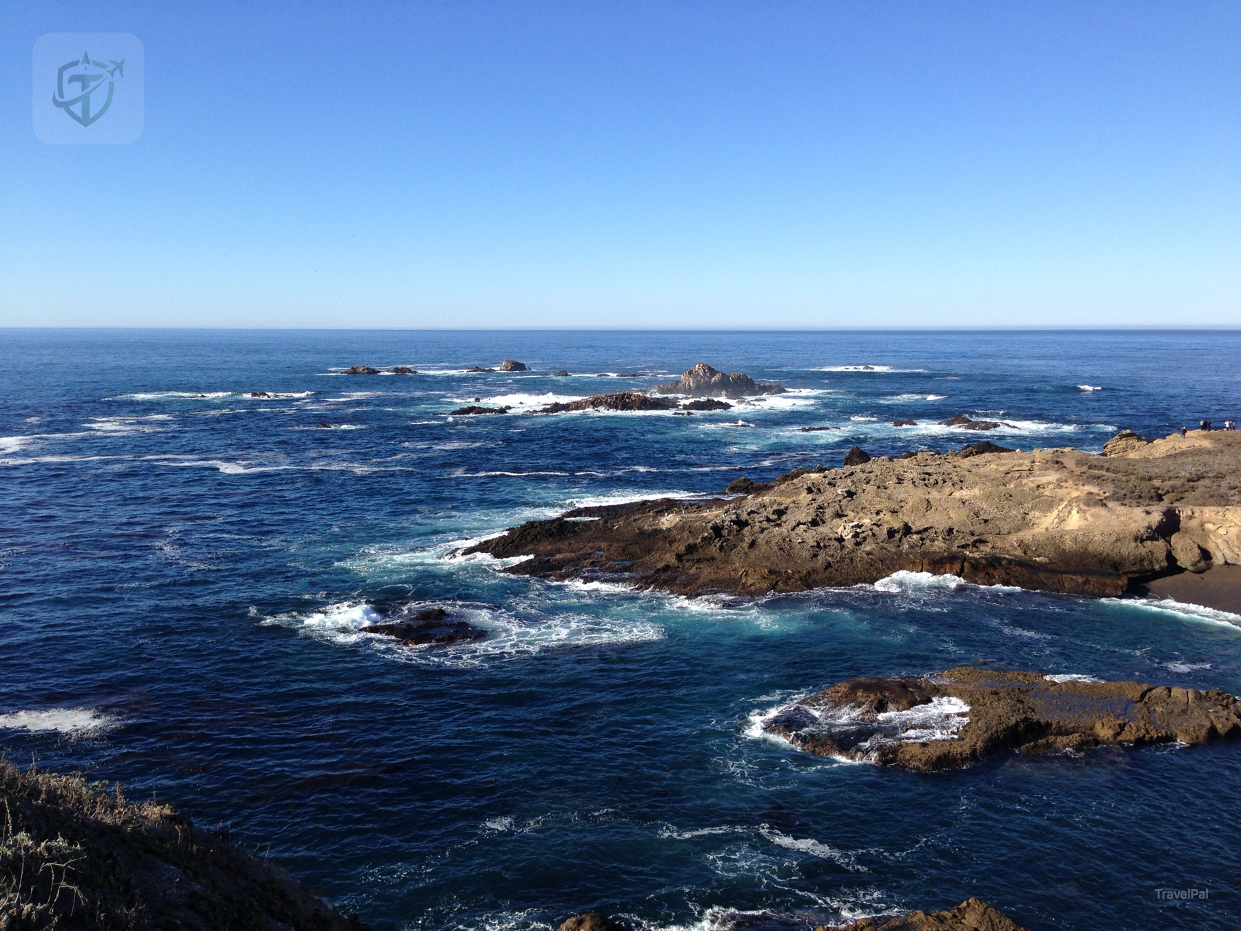 Layered cliffs and offshore rocks viewed from a coastal Highway 1 pullout