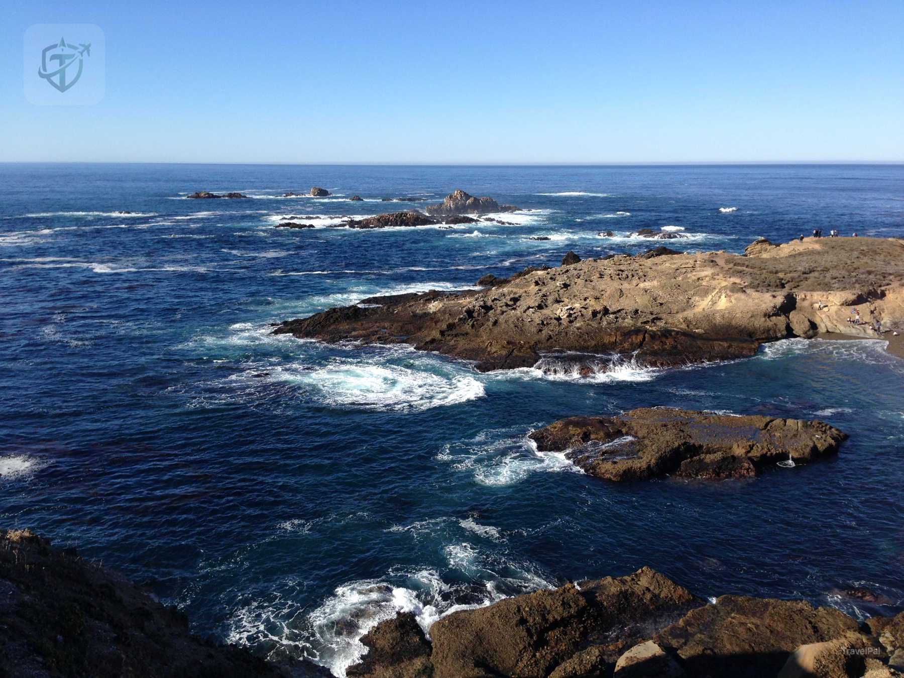 Flat offshore rock shelves surrounded by foaming blue water on the Big Sur coast