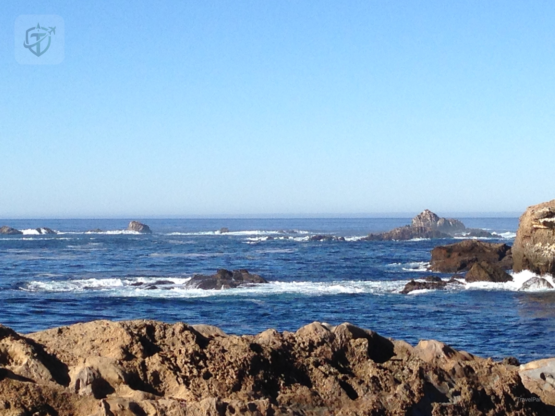 Low rocky shelf and tide pools beneath a clear blue Pacific horizon