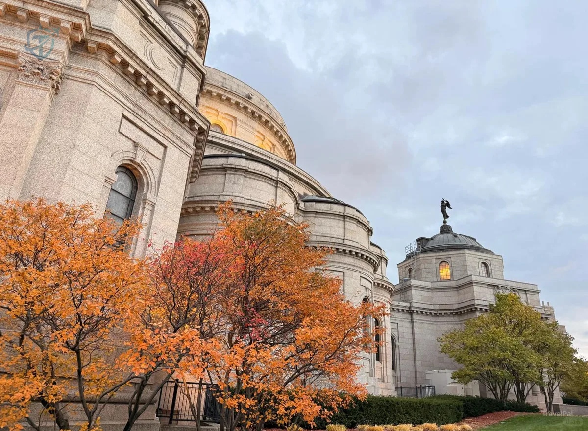 Curved granite exterior of the Cathedral of Saint Paul framed by autumn trees