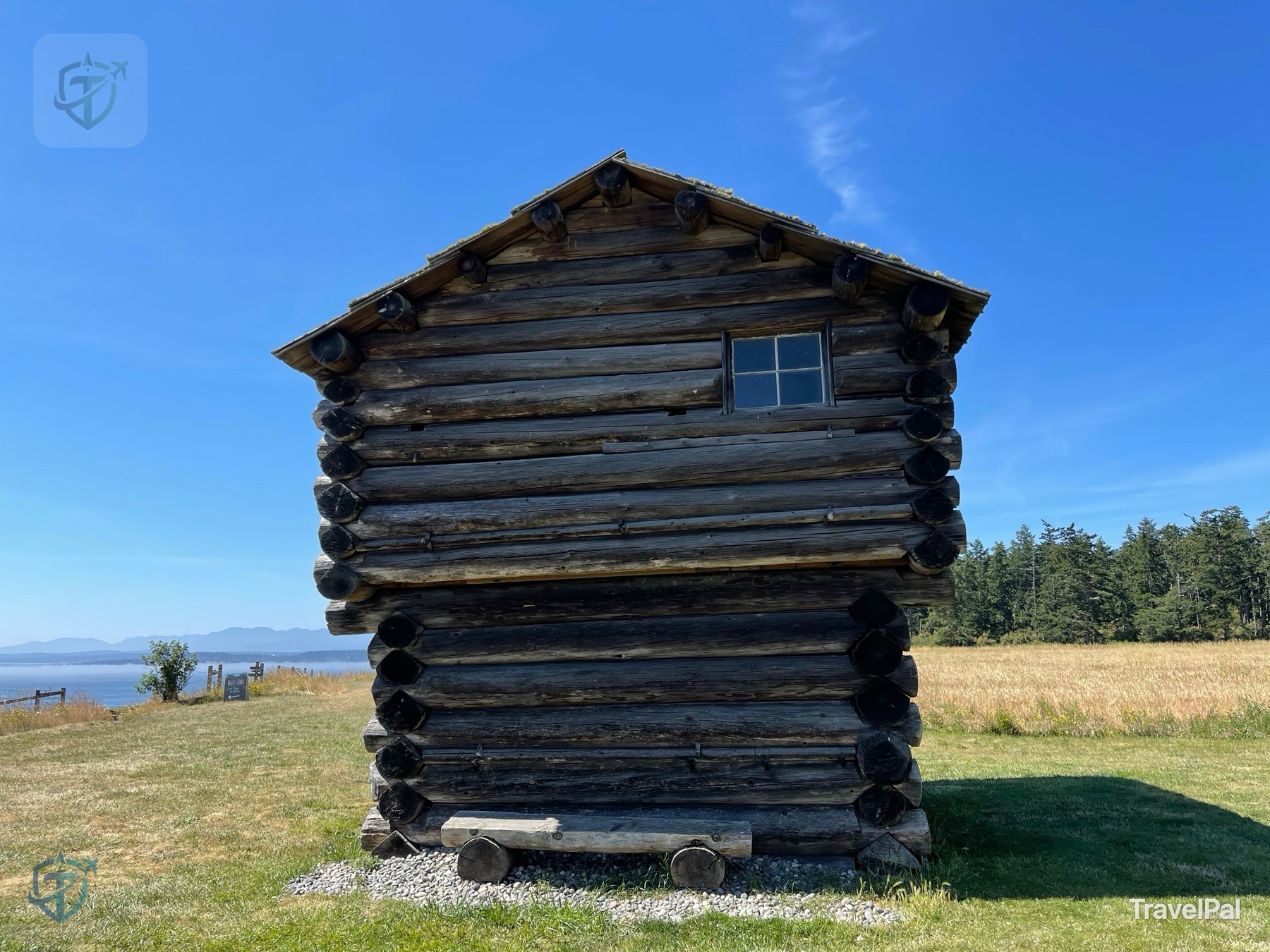 Weathered historic log structure standing beside a field and the water at Ebey’s Landing