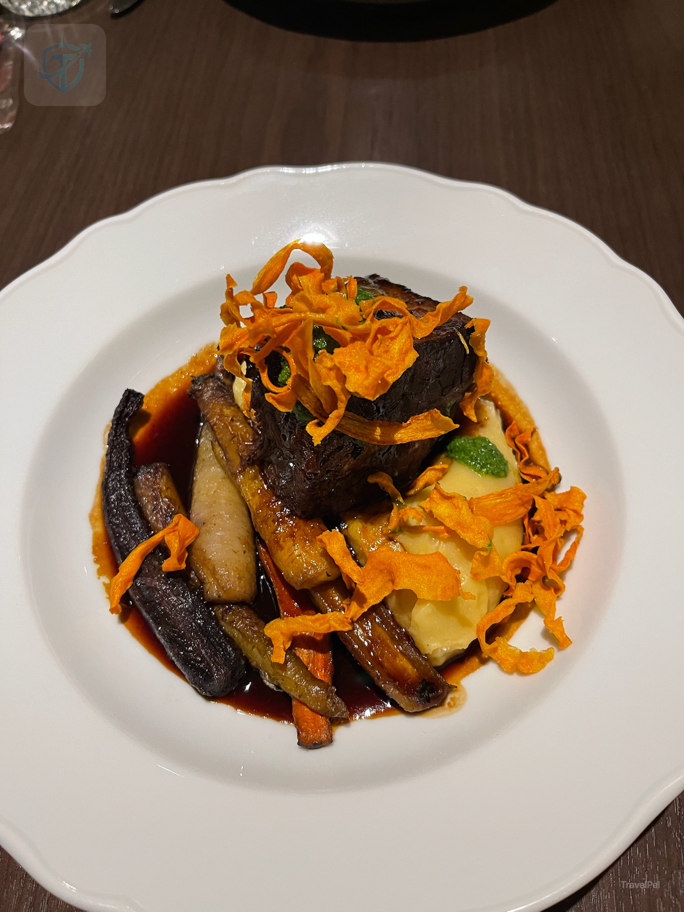 Plated beef dish with roasted vegetables, mushrooms, sauce, and crisp carrot garnish at Fairmont Banff Springs