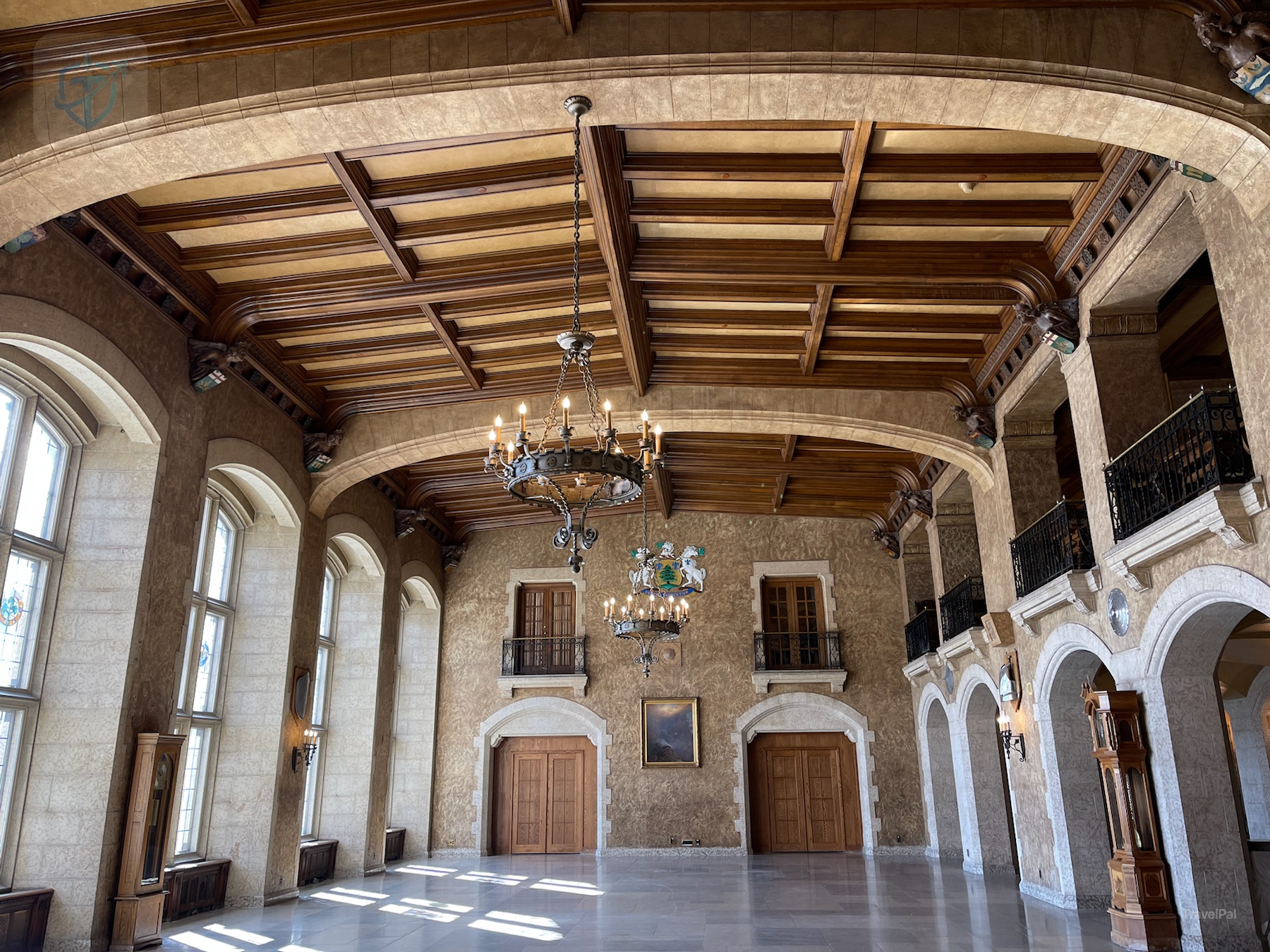 Grand interior hall at Fairmont Banff Springs with carved wood ceiling, stone arches, chandeliers, and a coat of arms