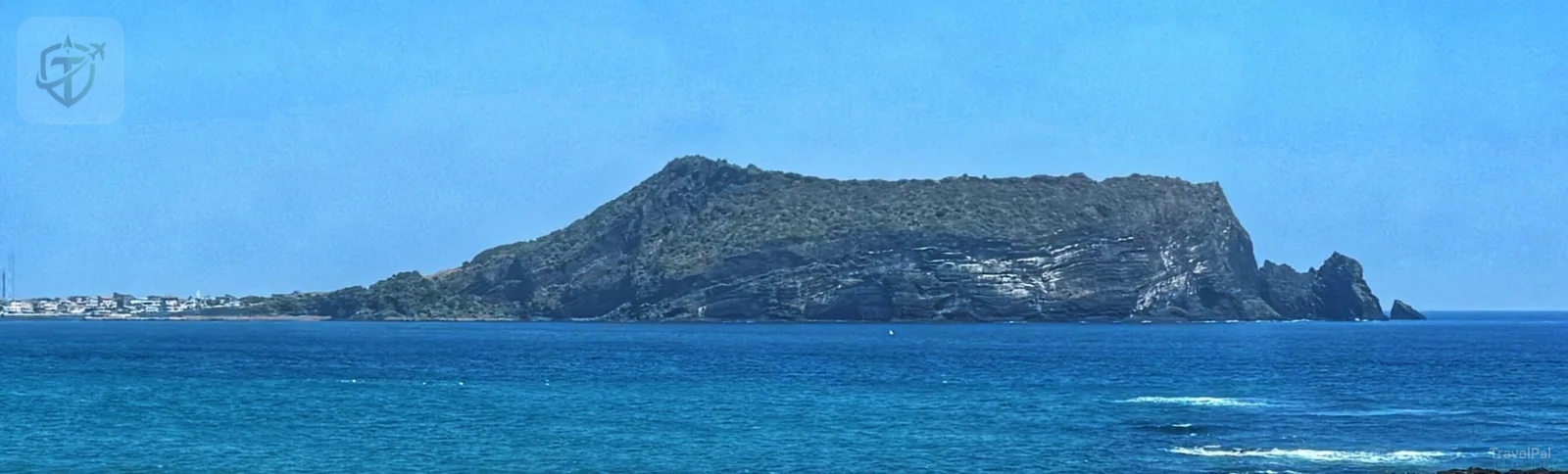 A volcanic hill rising across the blue water on Jeju Island