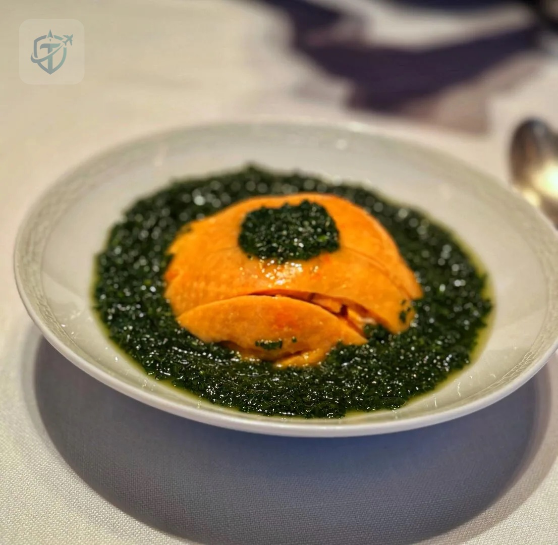 Orange seafood dish surrounded by dark green vegetables at Dining Room