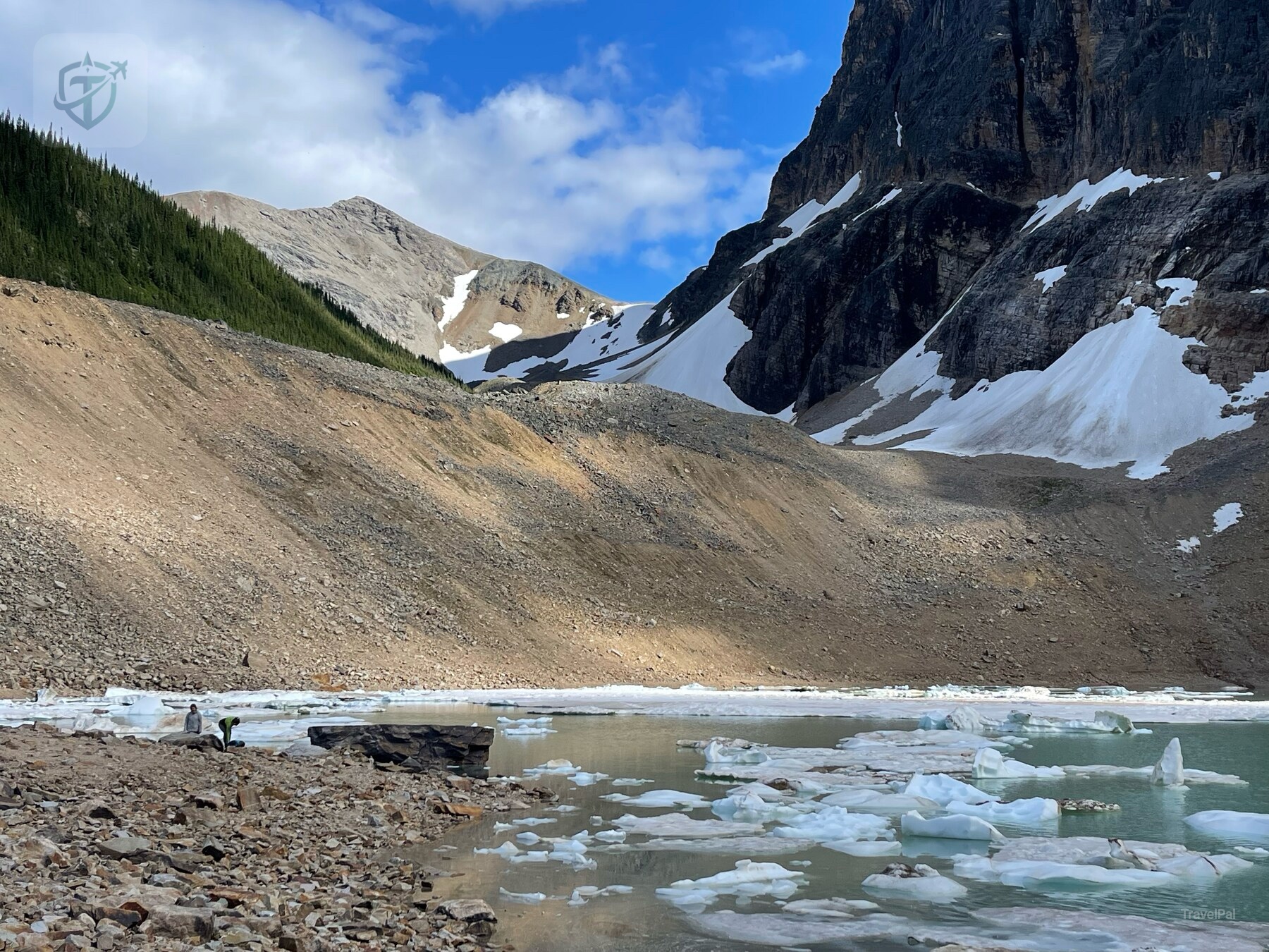 Pale turquoise glacier lake with ice fragments below a steep mountain basin