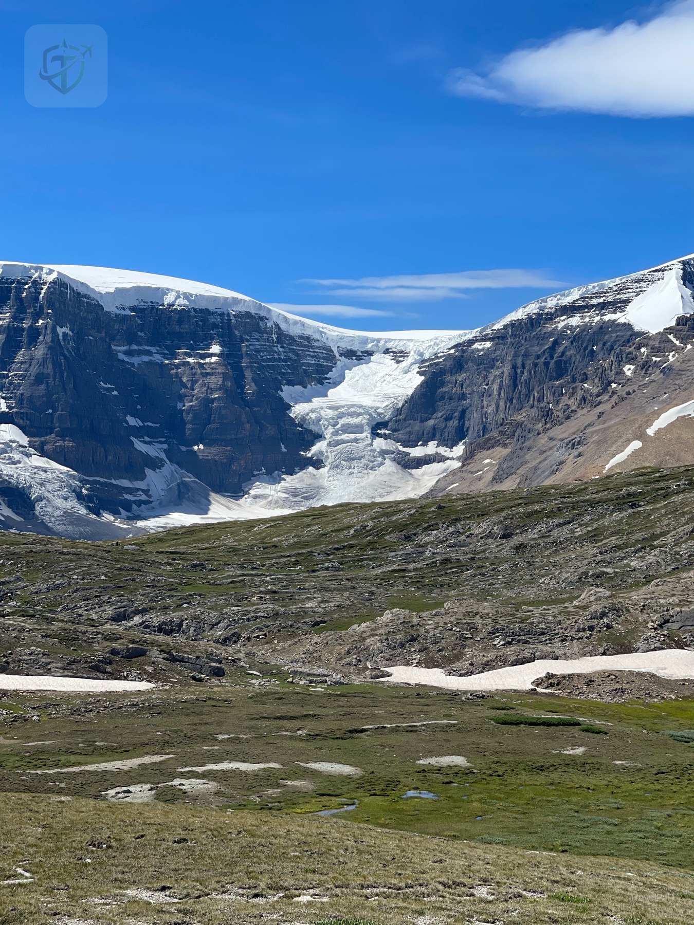 Vertical view into a broad glacial valley surrounded by snow-dusted cliffs
